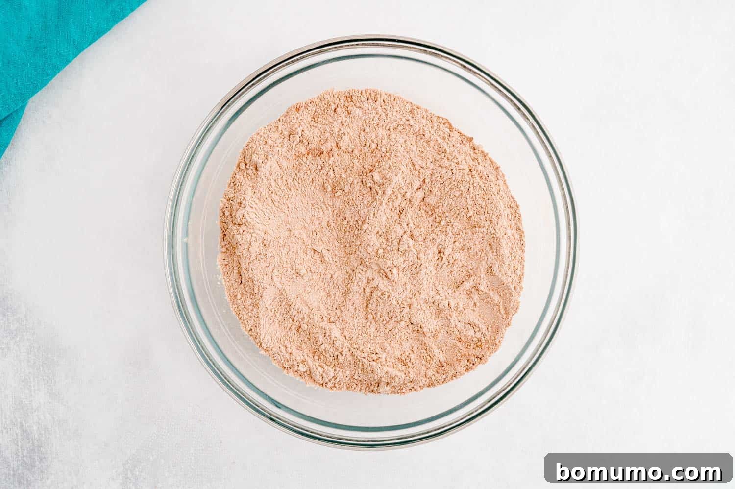 Dry ingredients, including flour and rich cocoa powder, meticulously whisked together in a clear bowl, creating a uniform mixture ready to be added to the wet components for the cookie dough.