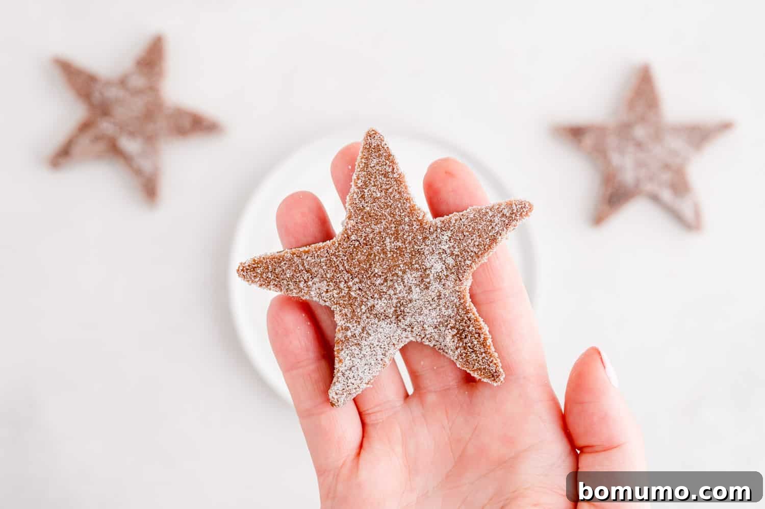 An unbaked chocolate peppermint sugar cookie, freshly dipped in sparkling granulated sugar, showcasing its festive appeal and readiness for the oven.
