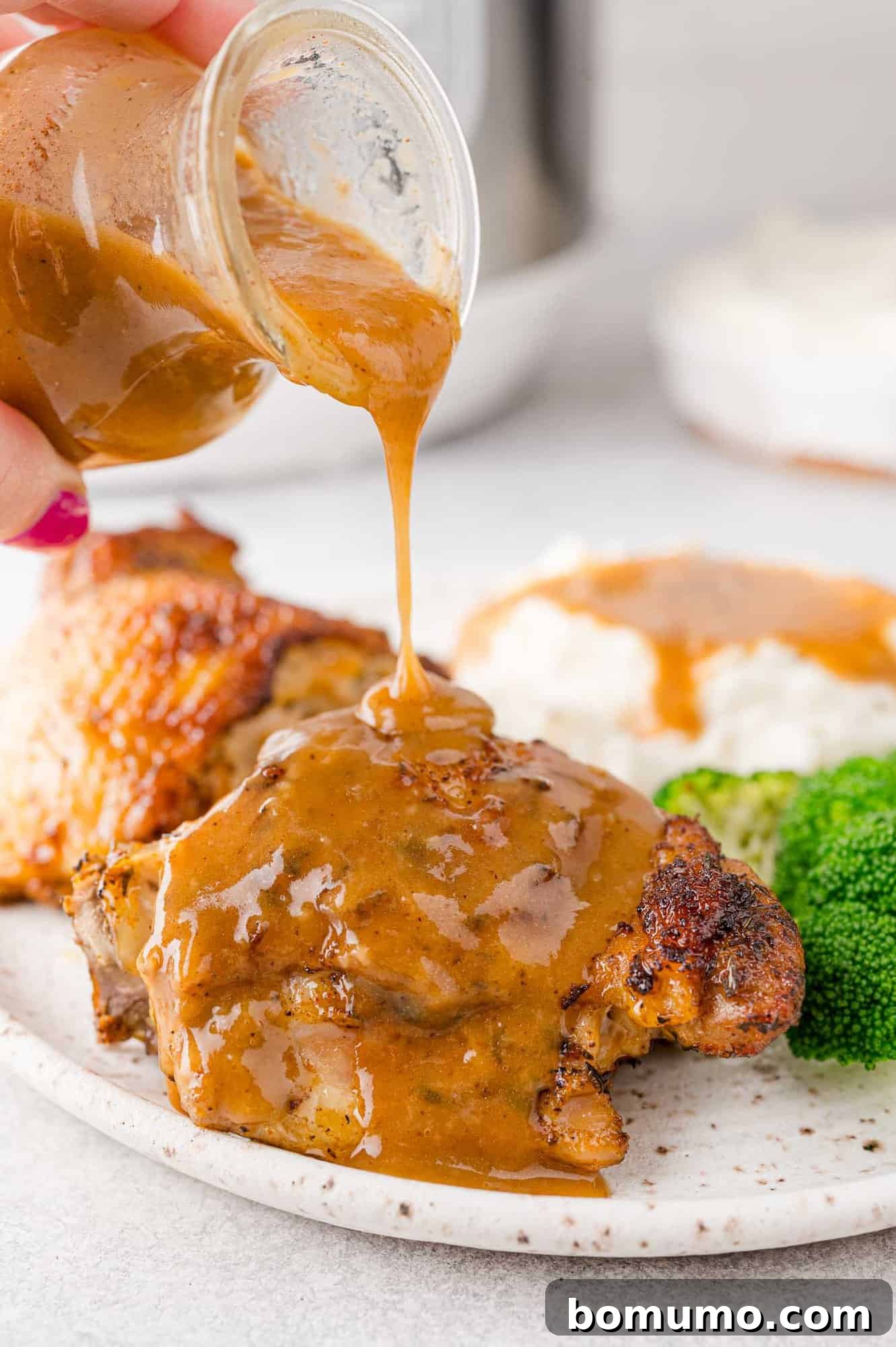 Gravy being poured on Instant Pot Chicken thighs.