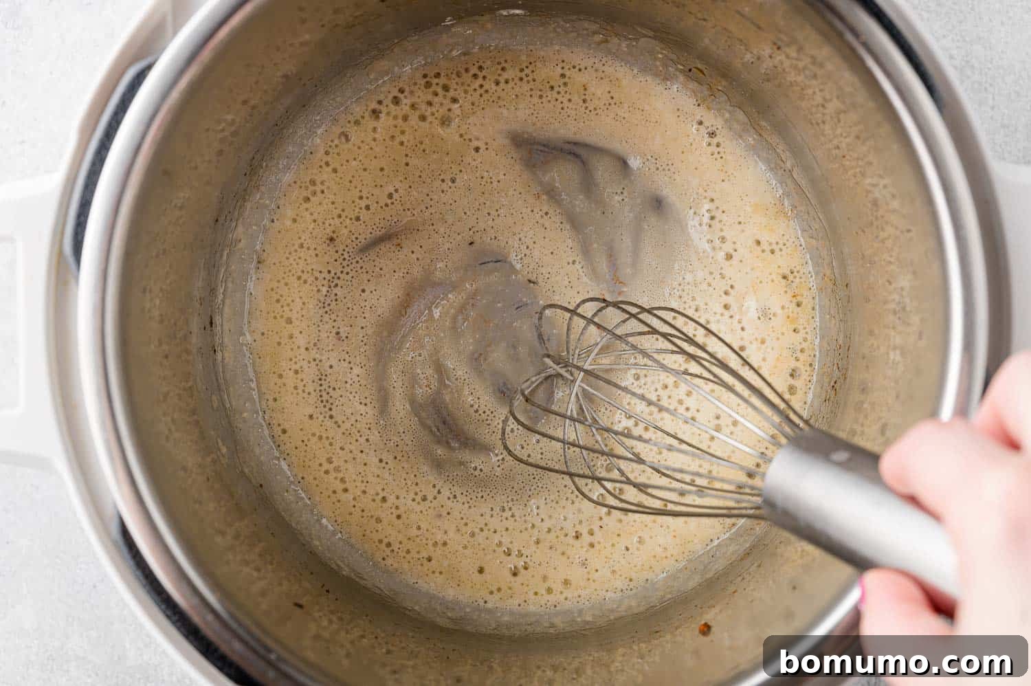 Flour added to Instant Pot, being whisked.
