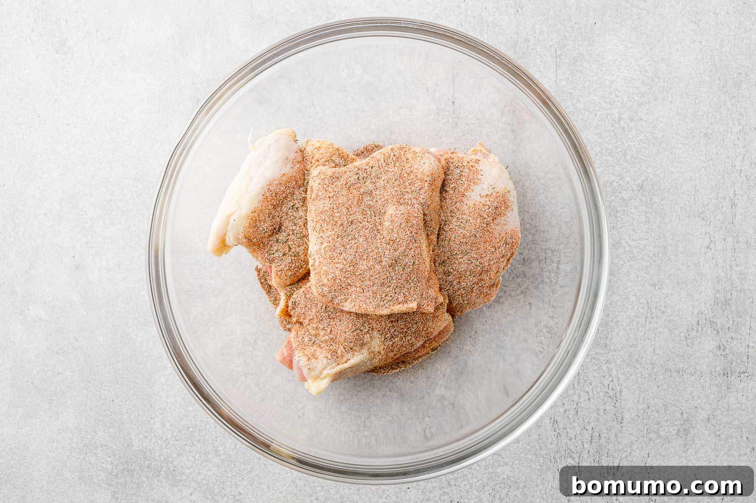 Raw chicken thighs rubbed with seasoning mixture.