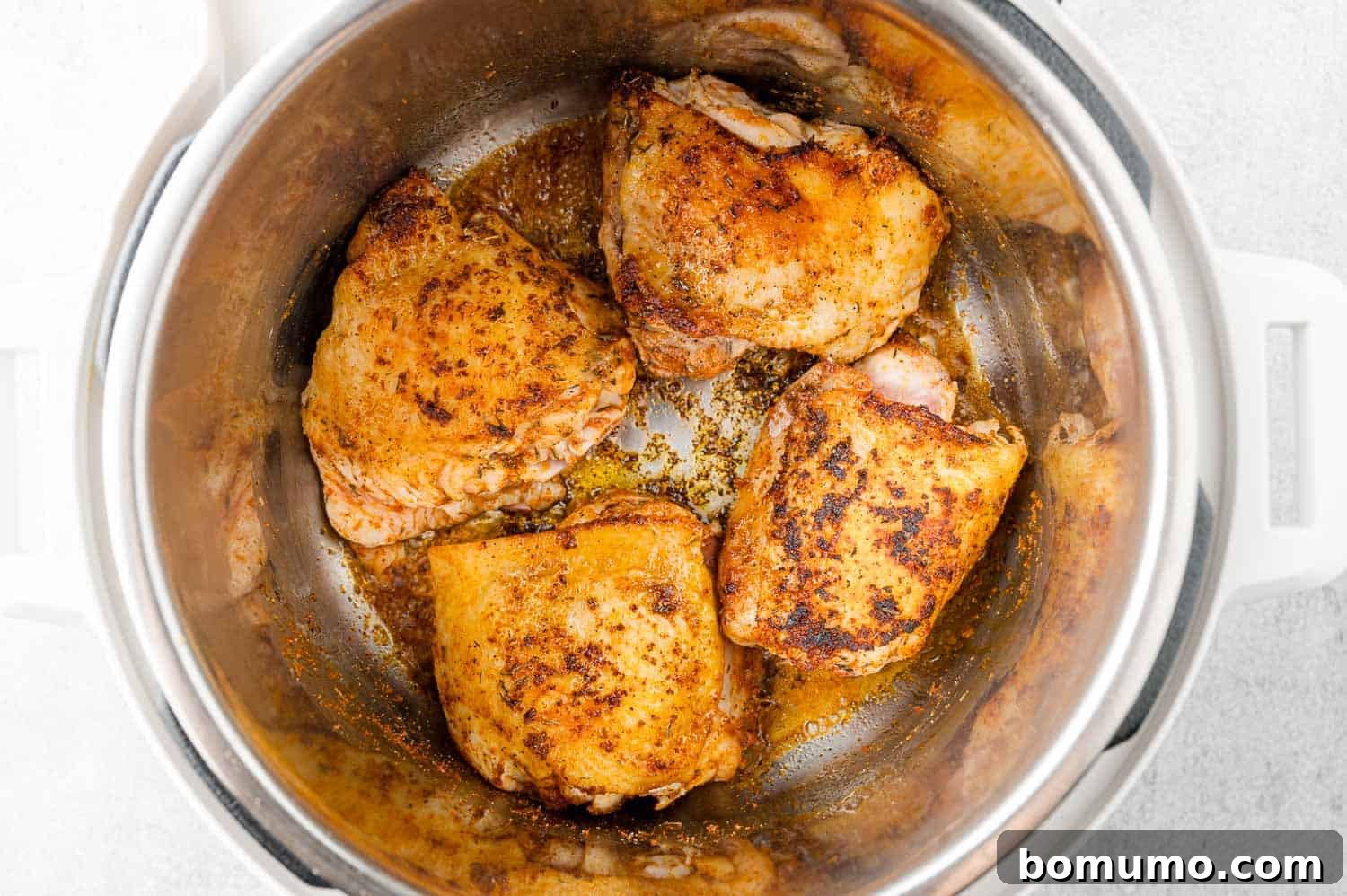 Chicken thighs being browned on the second side in the Instant Pot.