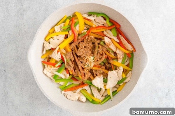 Garlic and jerk seasoning added to a skillet with chicken and sauteed bell peppers.