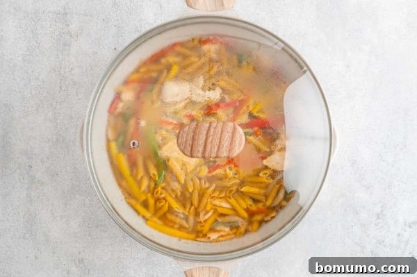Rasta Pasta ingredients simmering in a covered skillet.