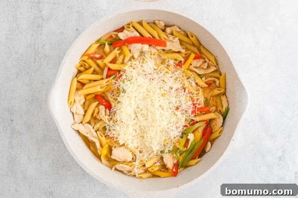 Cream and cheese added to a skillet with Rasta Pasta ingredients.