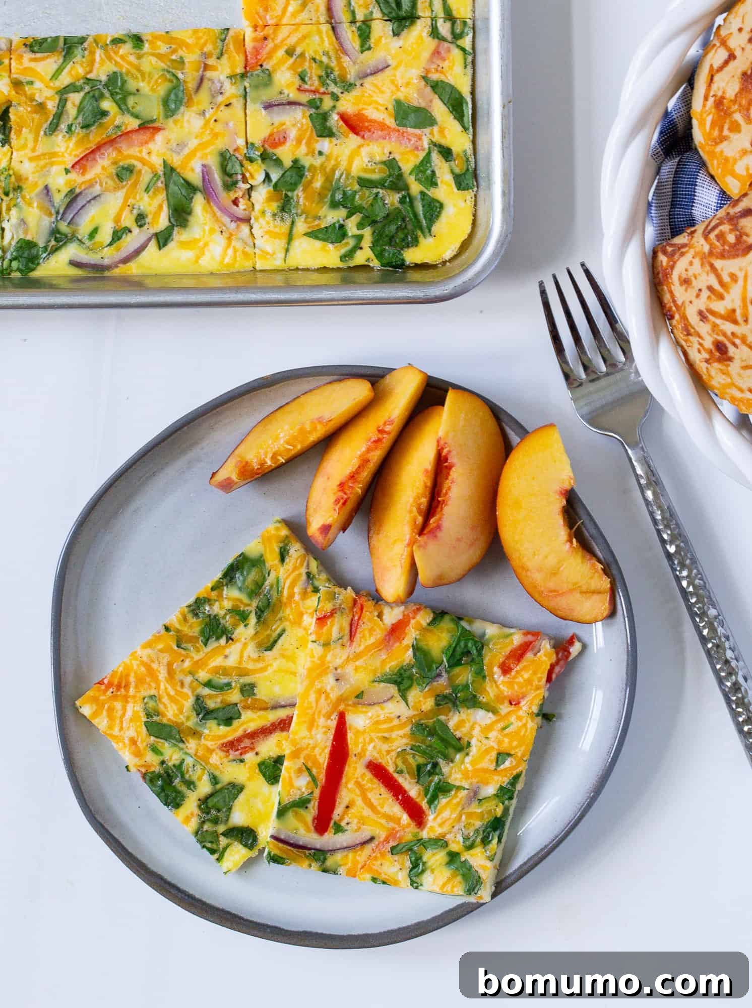 Golden sheet pan eggs served elegantly on a plate with fresh, juicy peaches for a delightful and easy breakfast.