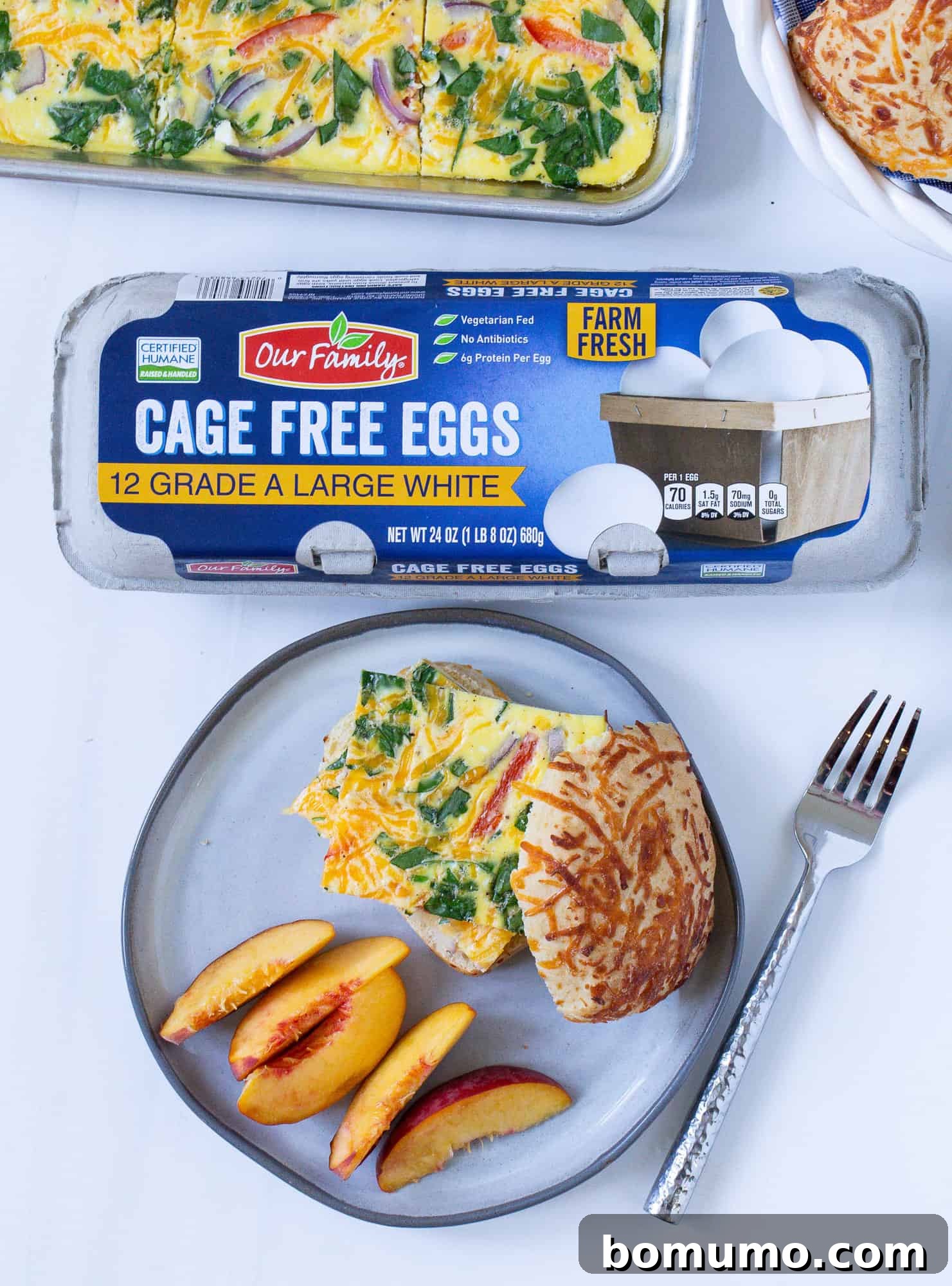 A freshly baked sheet pan of scrambled eggs, with a carton of farm-fresh eggs beside it, emphasizing the main ingredient.