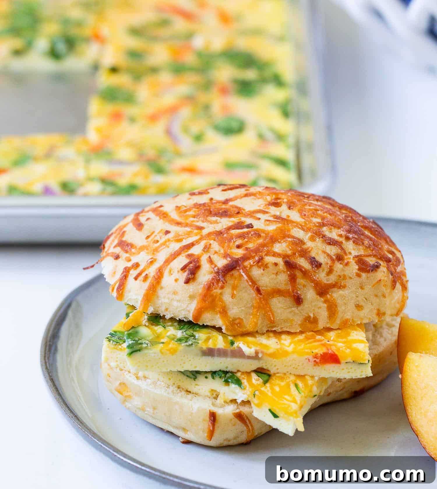 Fluffy sheet pan eggs, topped with melted cheese, served on a toasted bun for a quick and satisfying breakfast sandwich.