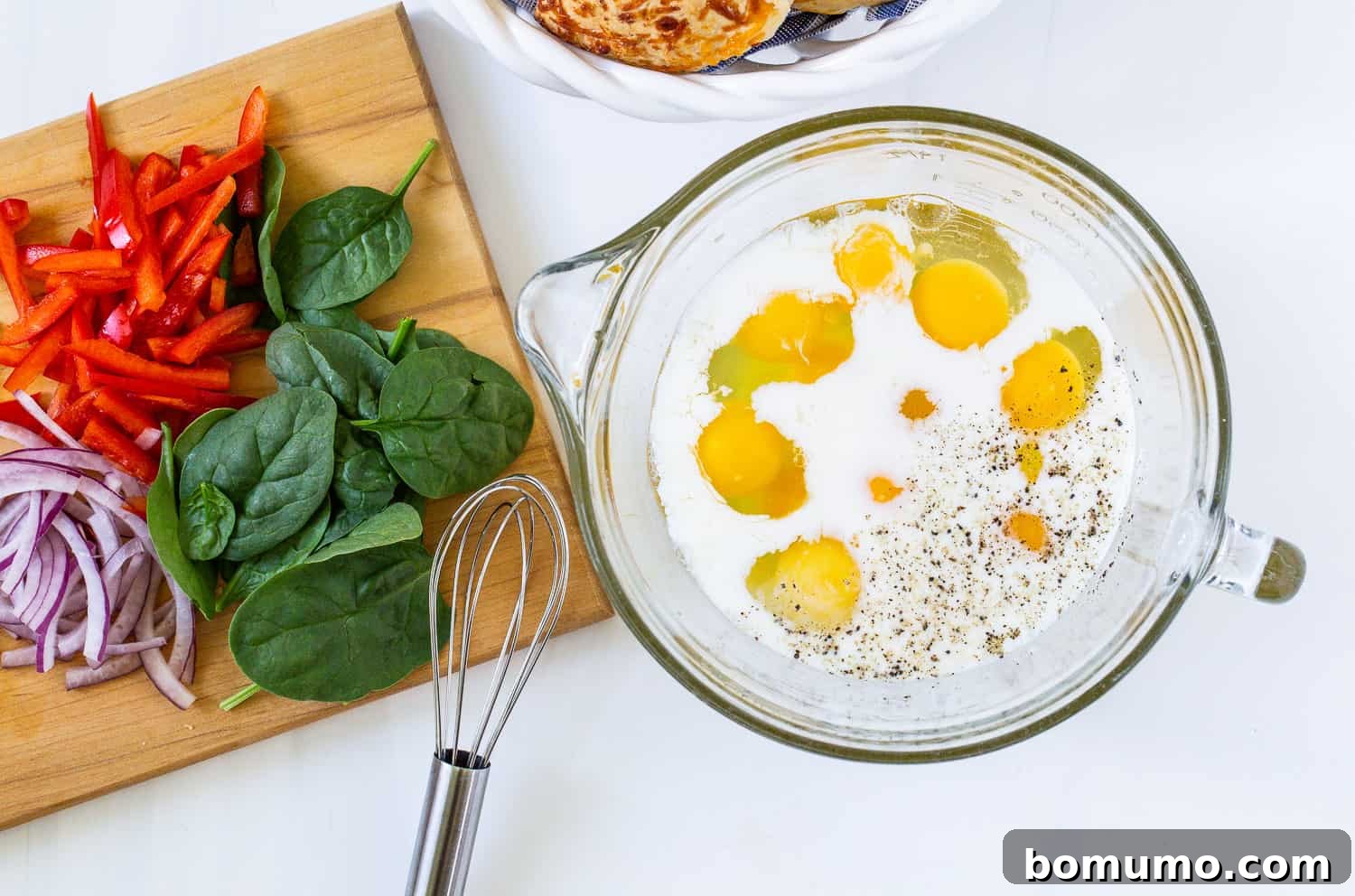 Raw eggs and milk ready for whisking in a large mixing bowl.