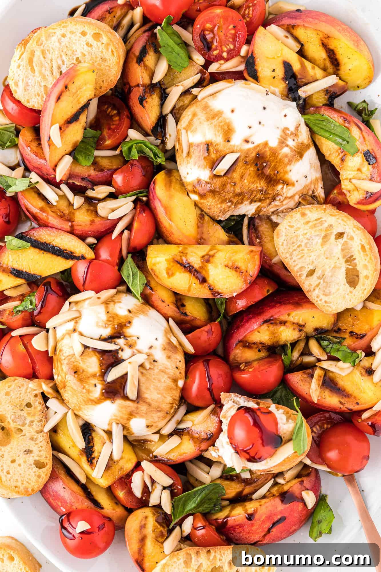 A gorgeous grilled peach and burrata salad platter, served with crispy crostini, highlighting its appeal as a light meal.