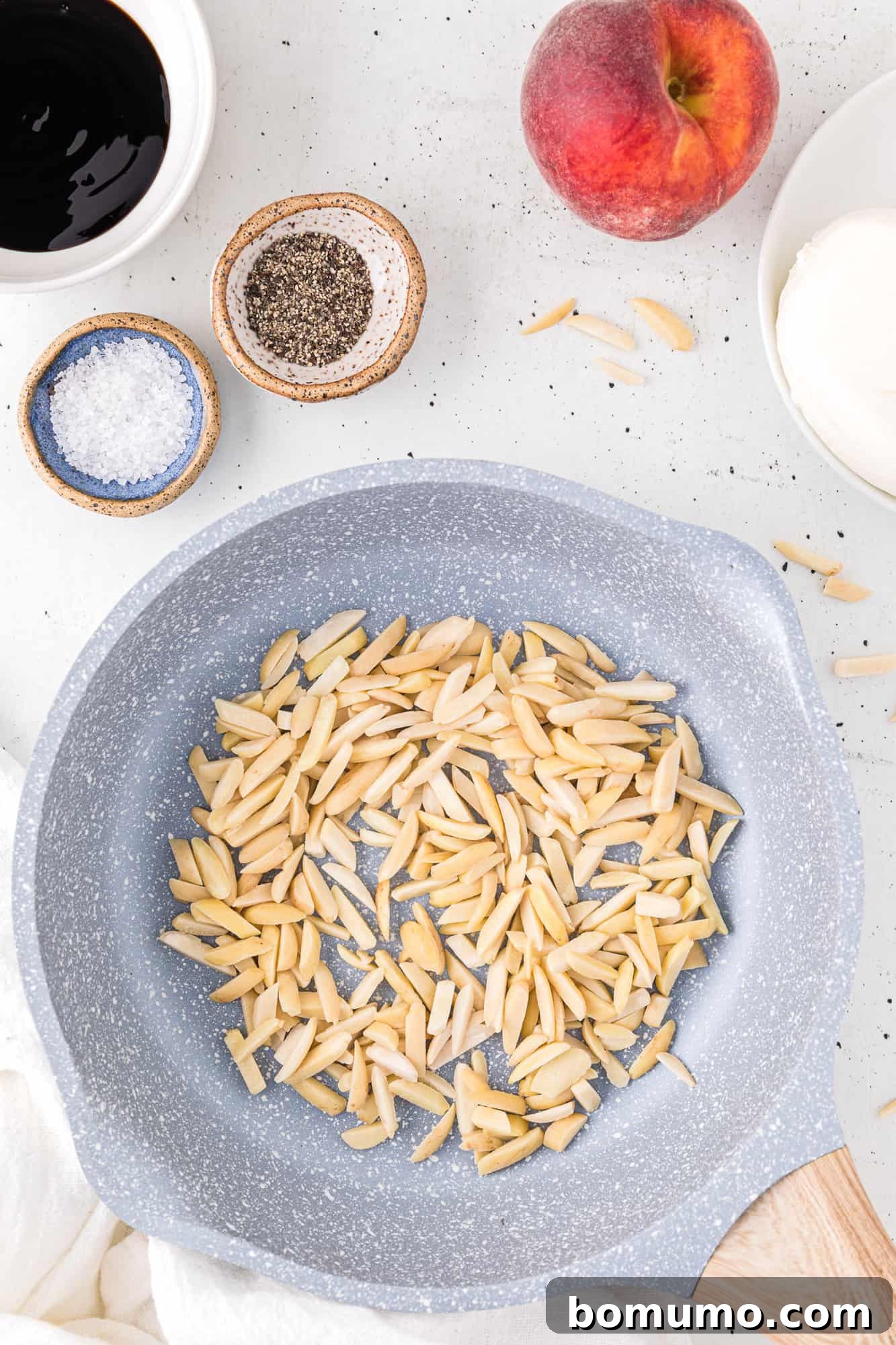 Slivered almonds being toasted in a small, dry skillet, turning golden brown.