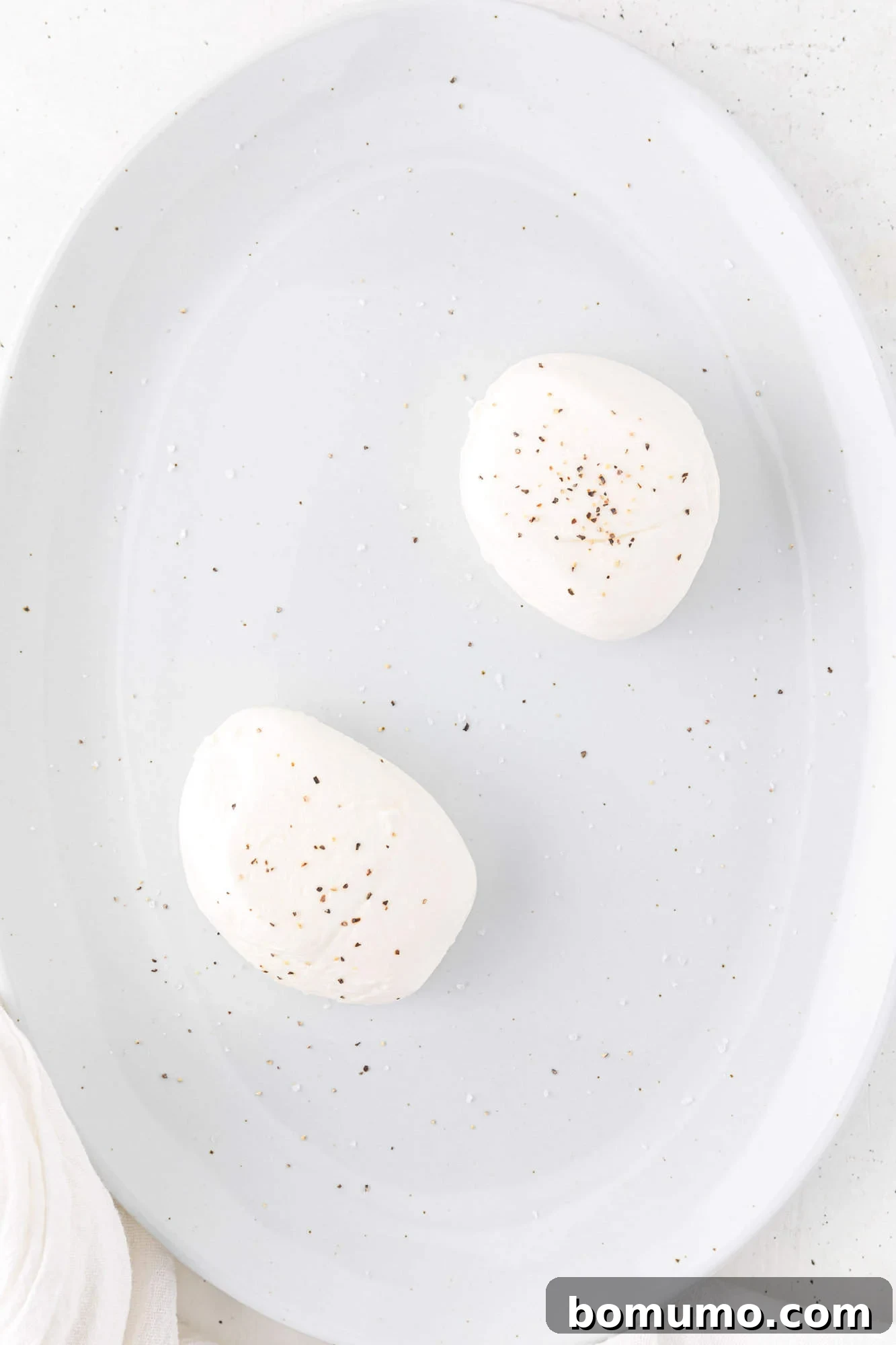 Fresh burrata cheese rounds carefully arranged on a large white platter, ready for the salad assembly.