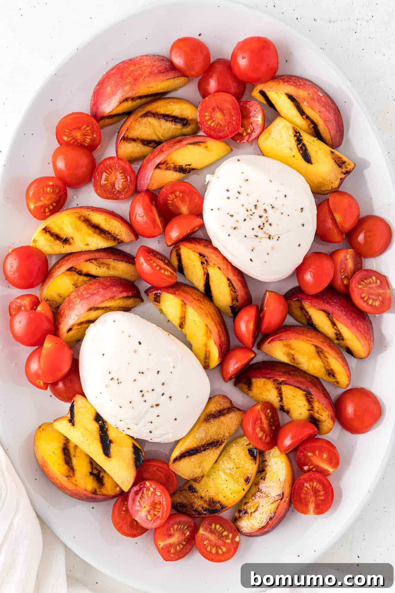 Seasoned cherry tomatoes added to the platter, nestled between the grilled peaches and burrata cheese to fill spaces and add color.