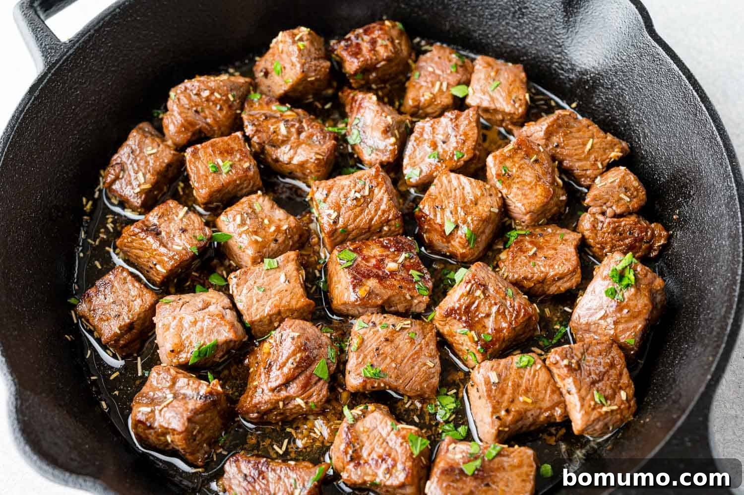 Garlic butter steak bites glistening in a black skillet, ready to be served.