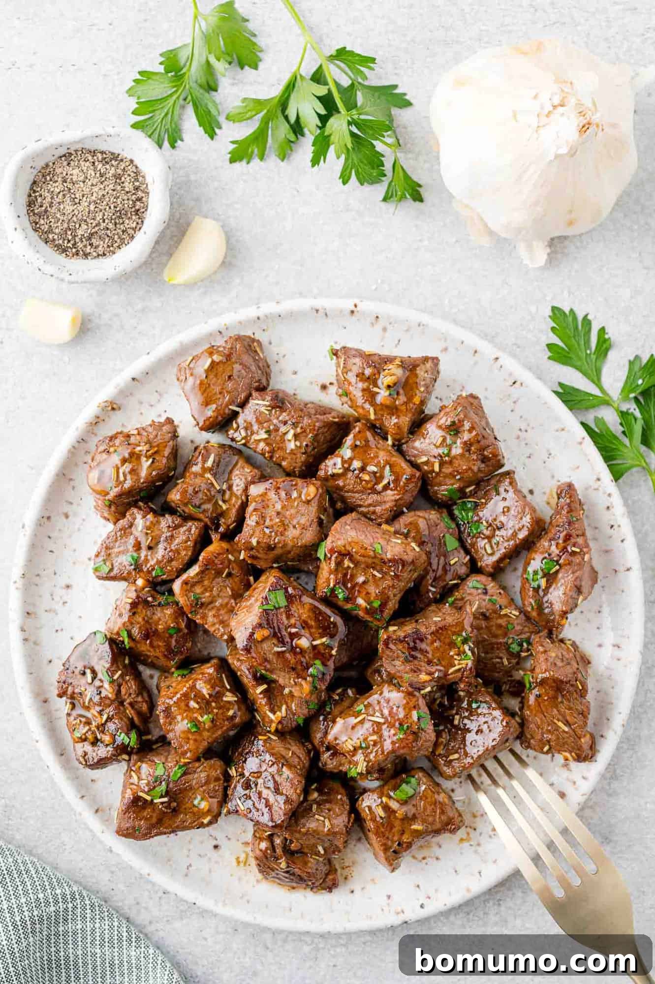 A stunning white serving platter brimming with succulent garlic butter steak bites, garnished with fresh parsley.