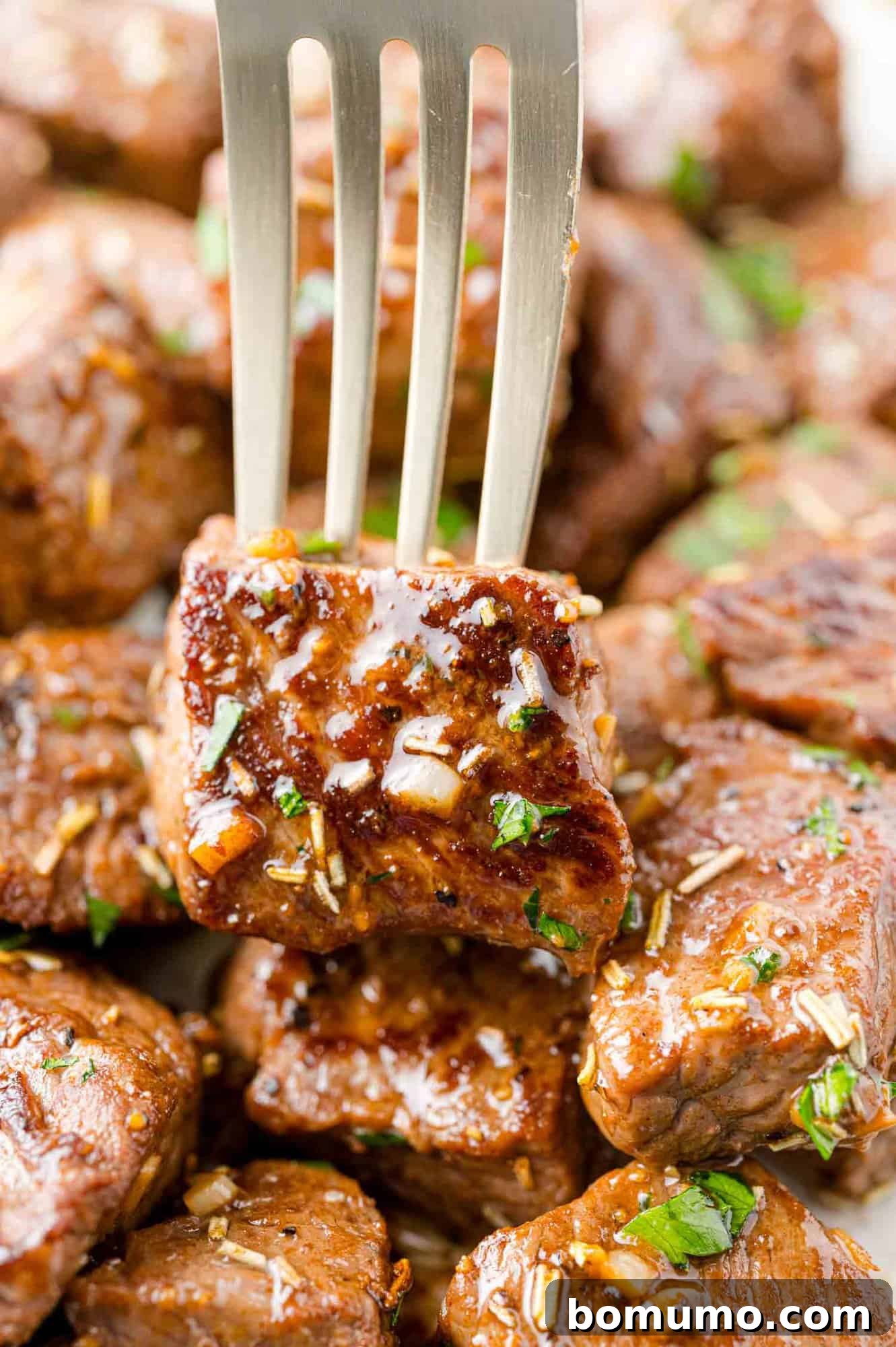 A perfectly cooked garlic butter steak bite speared on a fork, showing its tender interior.