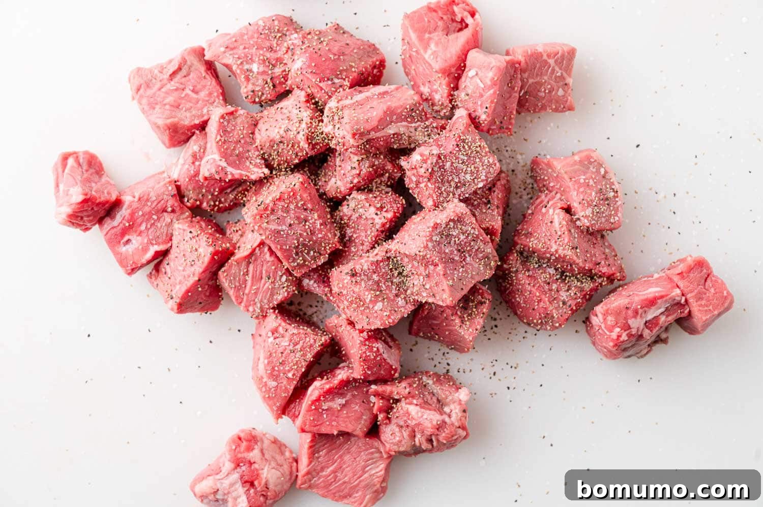 Uncooked steak bites, meticulously seasoned with salt and pepper, ready for searing.