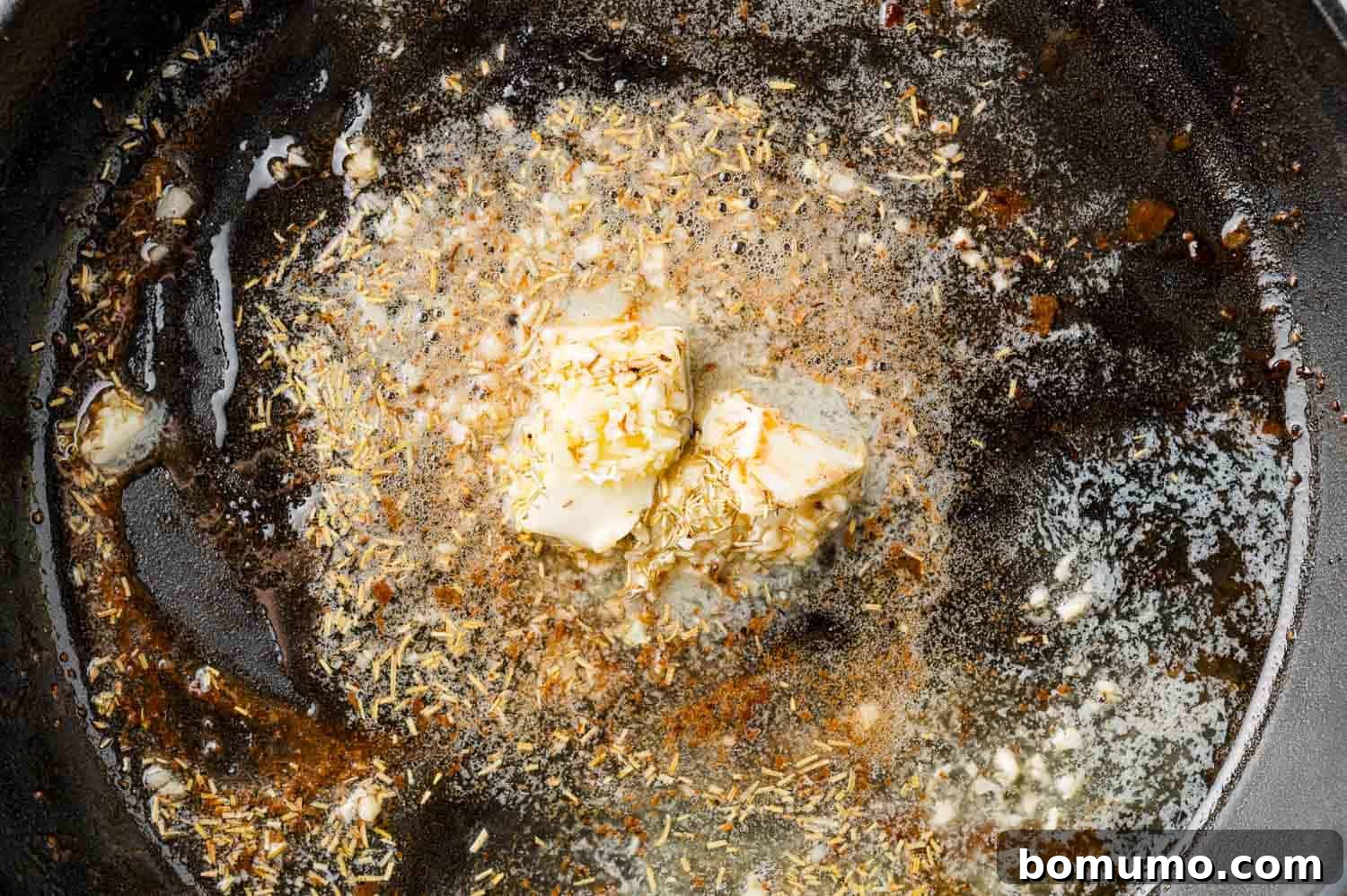 Unmelted butter, minced garlic, and dried rosemary waiting to infuse in a pan.