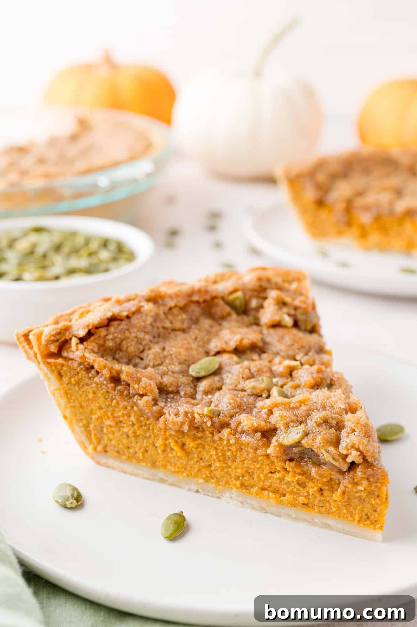 Slice of pumpkin pie with streusel on a plate.