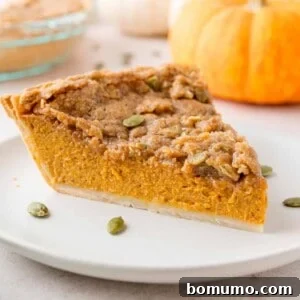 Slice of pumpkin pie with streusel on a white plate.