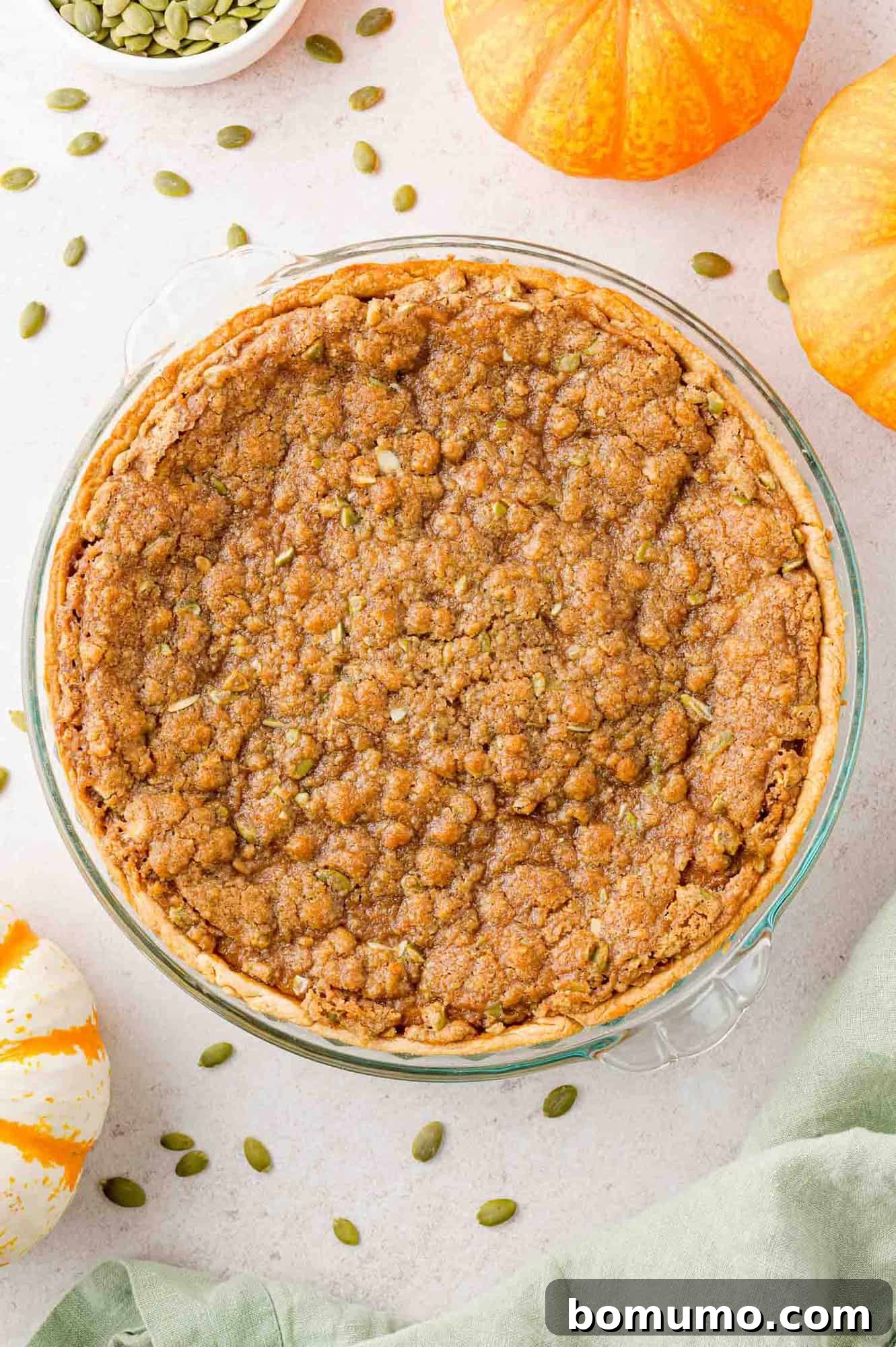 Overhead view of entire unsliced pumpkin pie, with streusel topping.