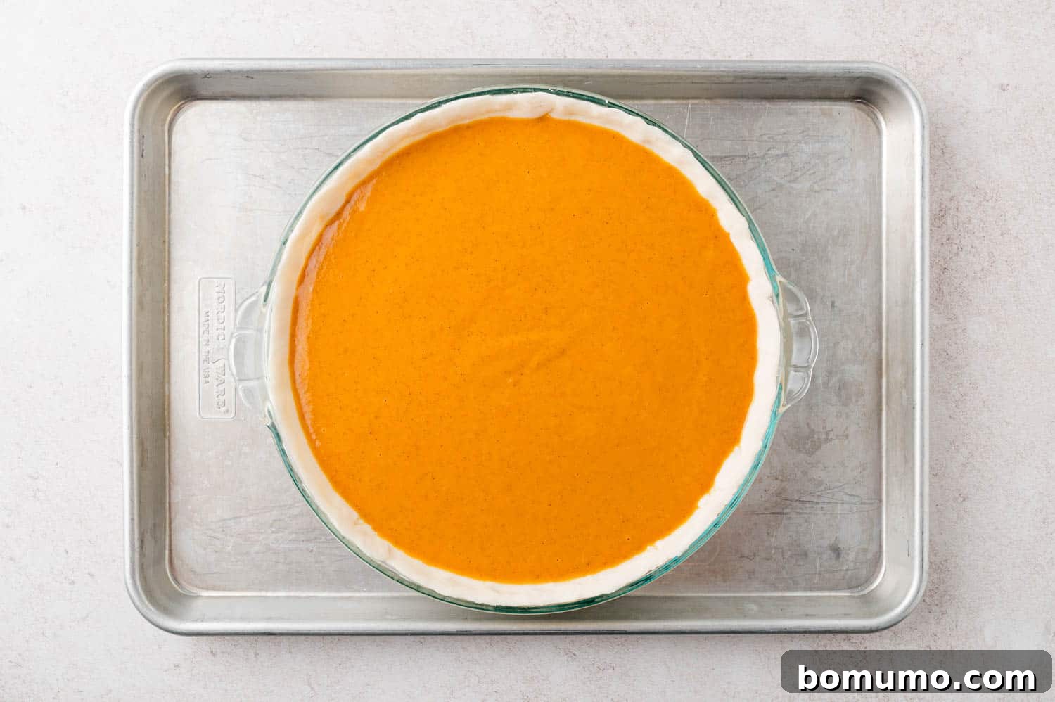 Unbaked pumpkin pie on a sheet pan.