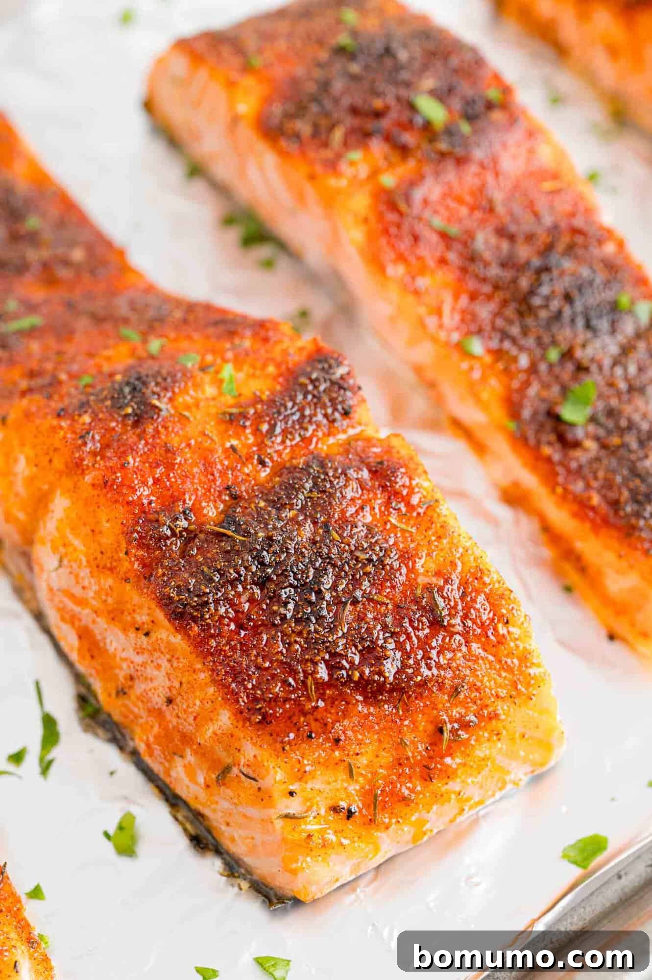 Close up of broiled salmon filets on a foil-lined baking sheet.