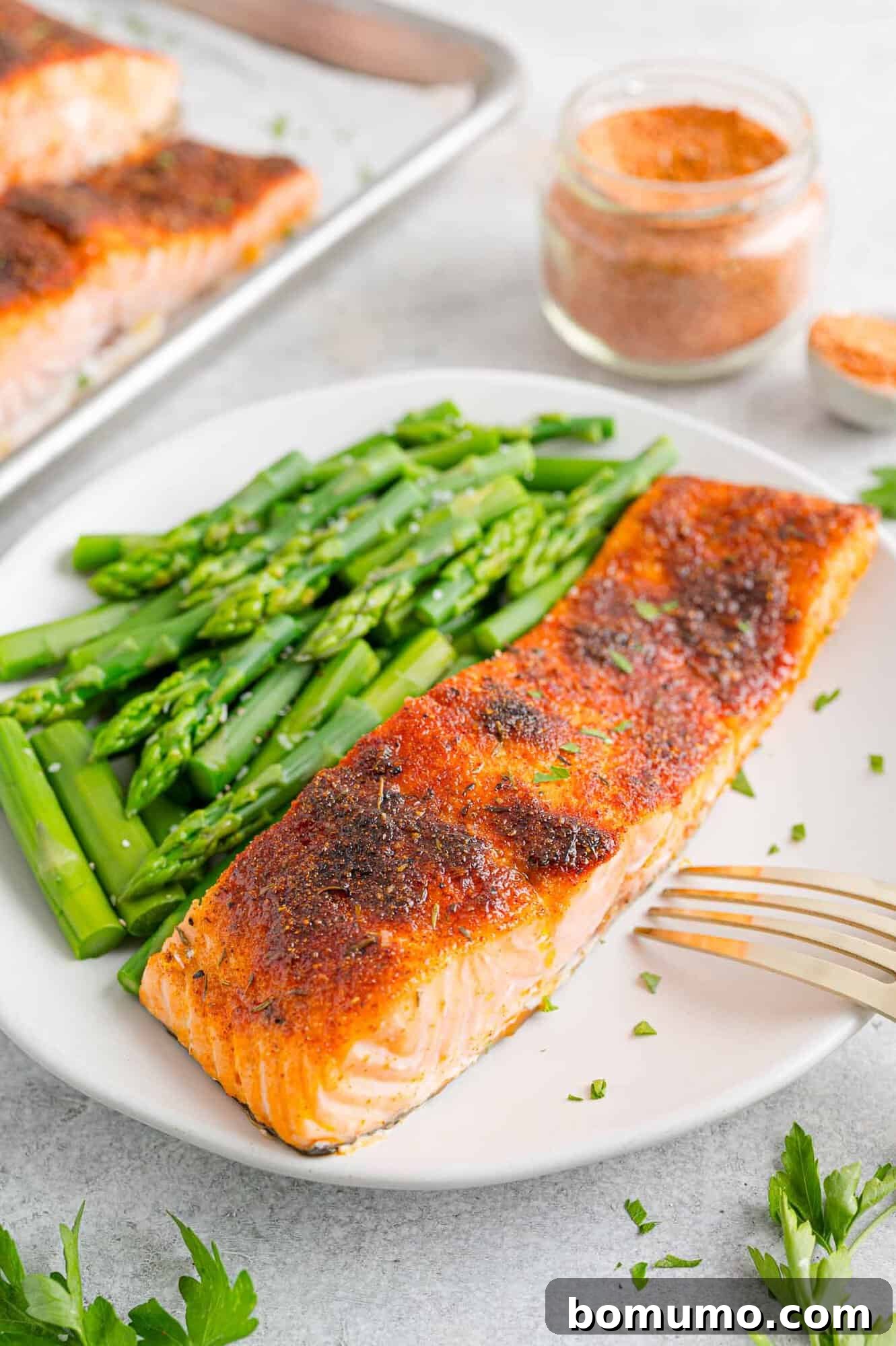 A broiled salmon filet with a side of green beans on a white plate.