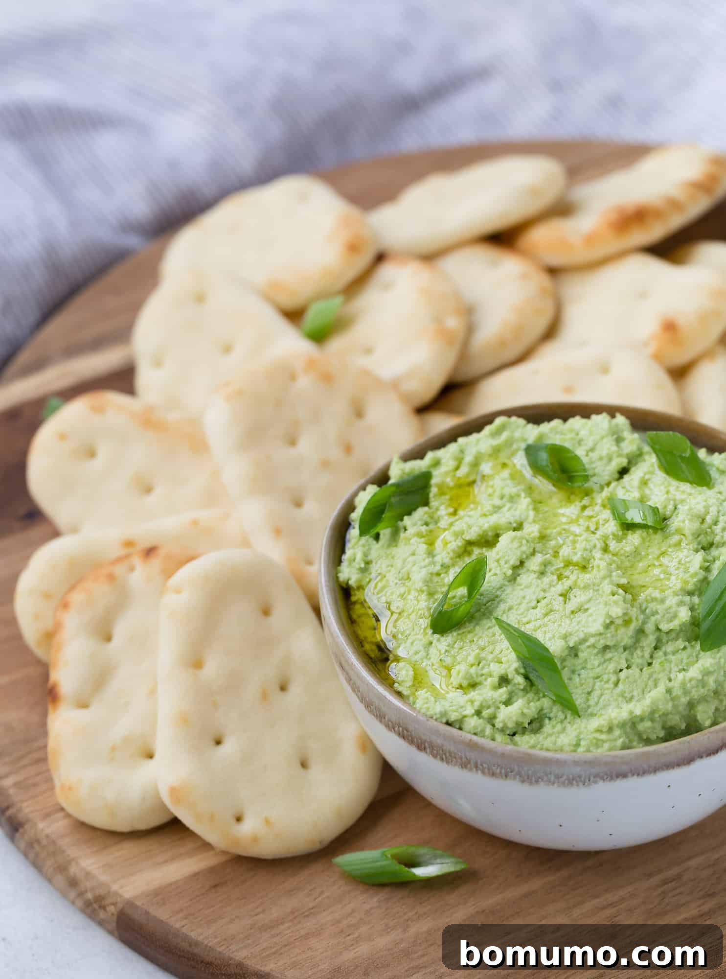 Vibrant Edamame Dip 2 Bright green edamame dip served alongside small pita bread wedges and fresh vegetables.