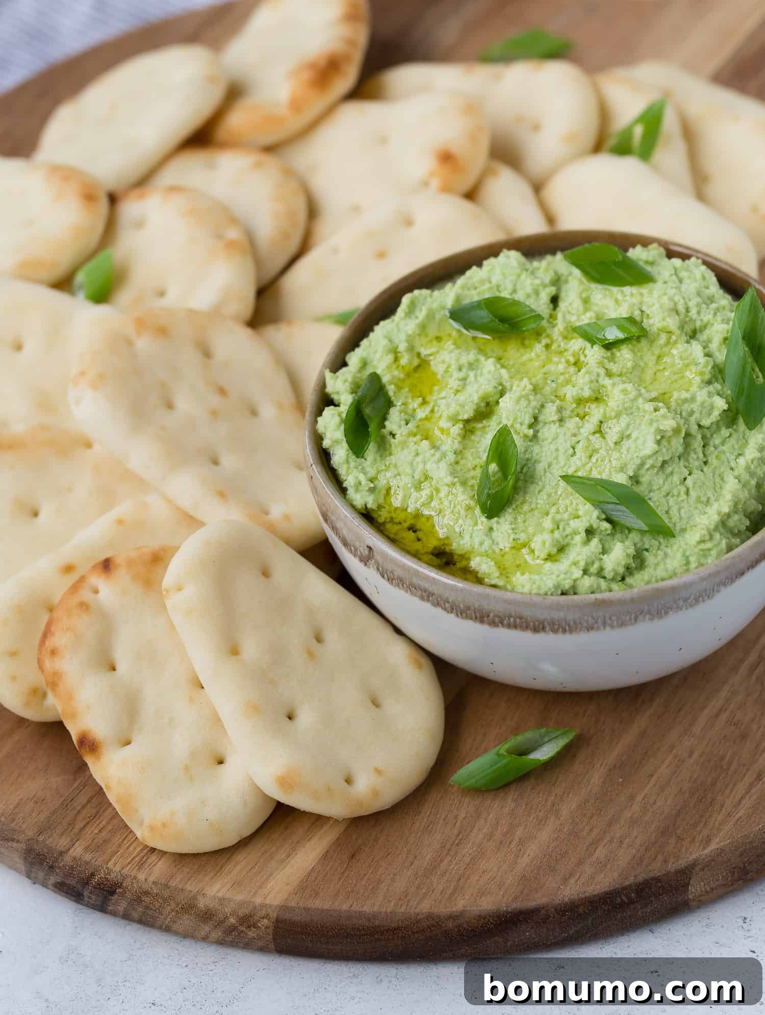 Vibrant Edamame Dip 3 Creamy green edamame dip topped with freshly chopped green onions, ready for serving.