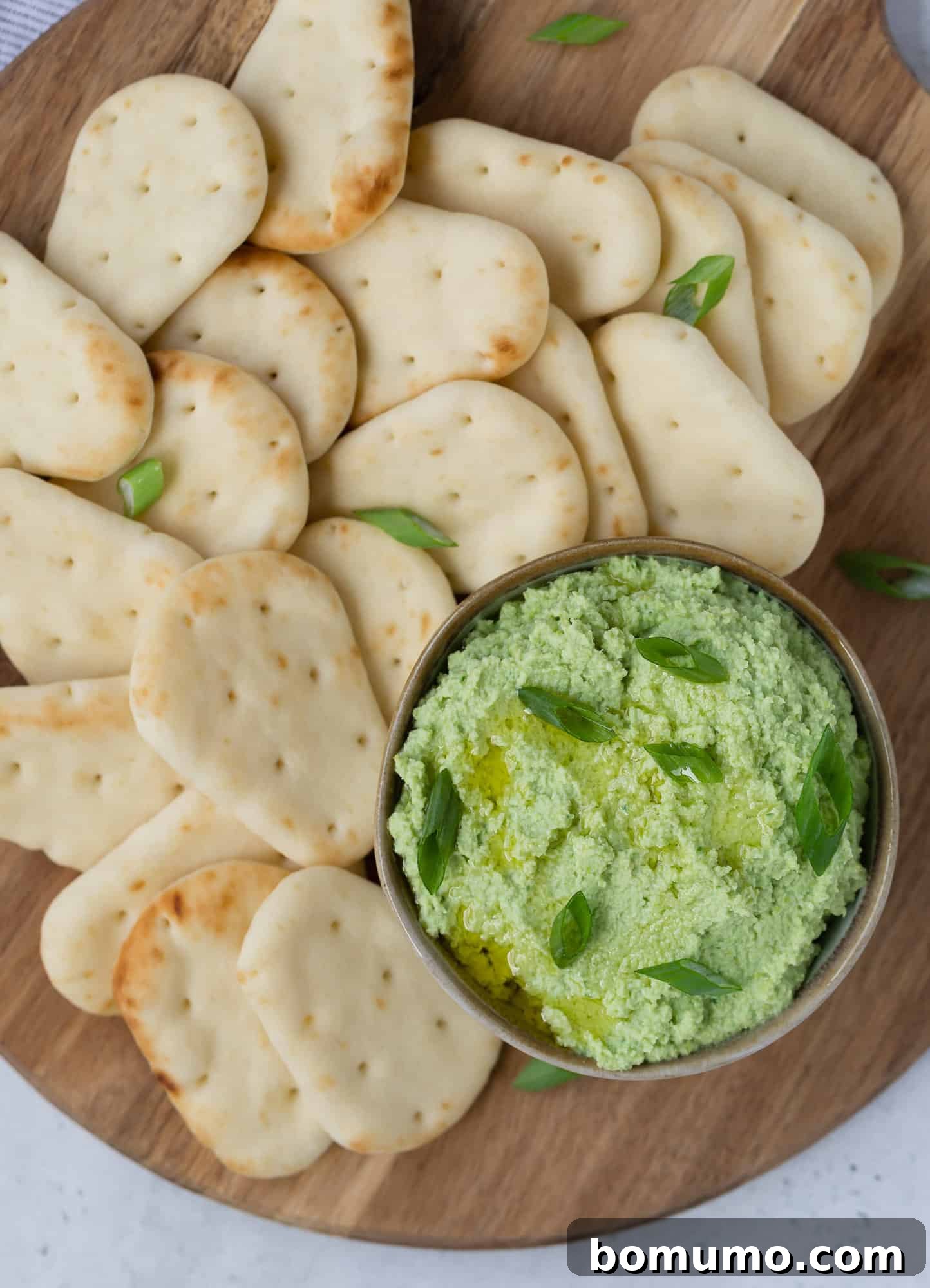 Vibrant Edamame Dip 4 Overhead view of a bowl of edamame dip artfully arranged with mini pitas for easy dipping.