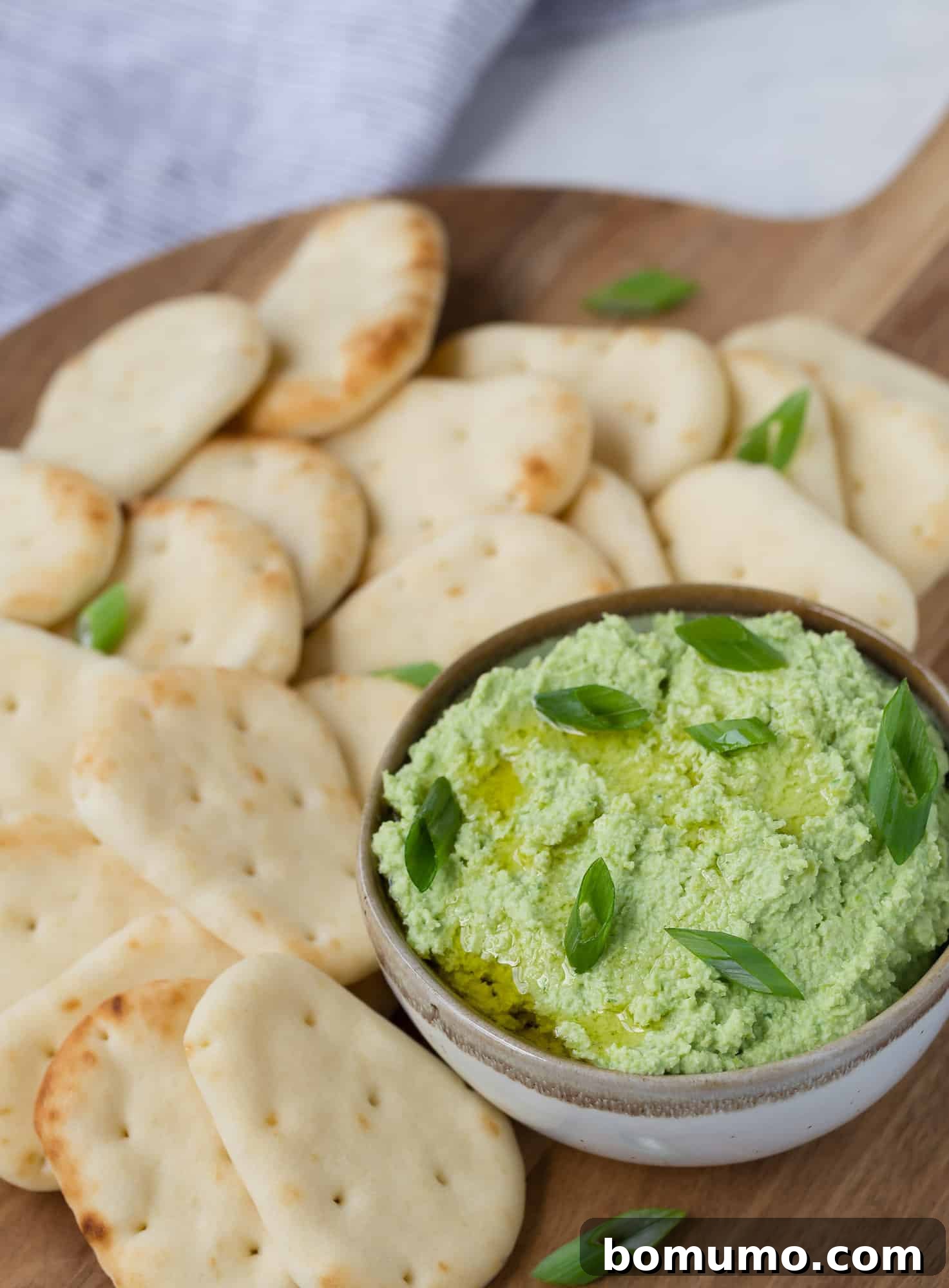 Vibrant Edamame Dip 5 Close-up of edamame dip drizzled with olive oil and garnished with fresh herbs, showcasing its creamy texture.