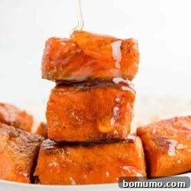 A delectable stack of salmon bites being generously drizzled with spicy hot honey, creating a glossy finish.