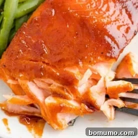Perfectly cooked BBQ salmon, flaked with a fork to reveal its juicy, tender texture.