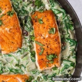 Overhead view of perfectly seared salmon settled in a rich, vibrant bed of spinach cream sauce.