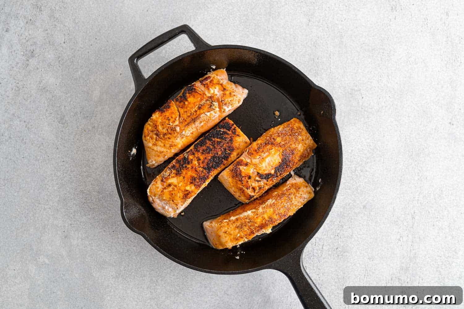 Perfectly seared salmon filets in a non-stick skillet, showcasing a golden-brown crust.