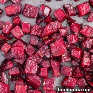 Roasted beets on a sheet pan, sprinkled with fresh rosemary, ready to be served.