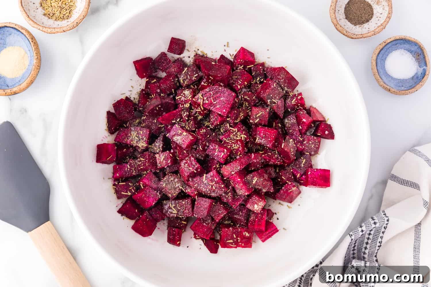 Cubed beets in a bowl, glistening with oil and seasonings, ready for roasting.