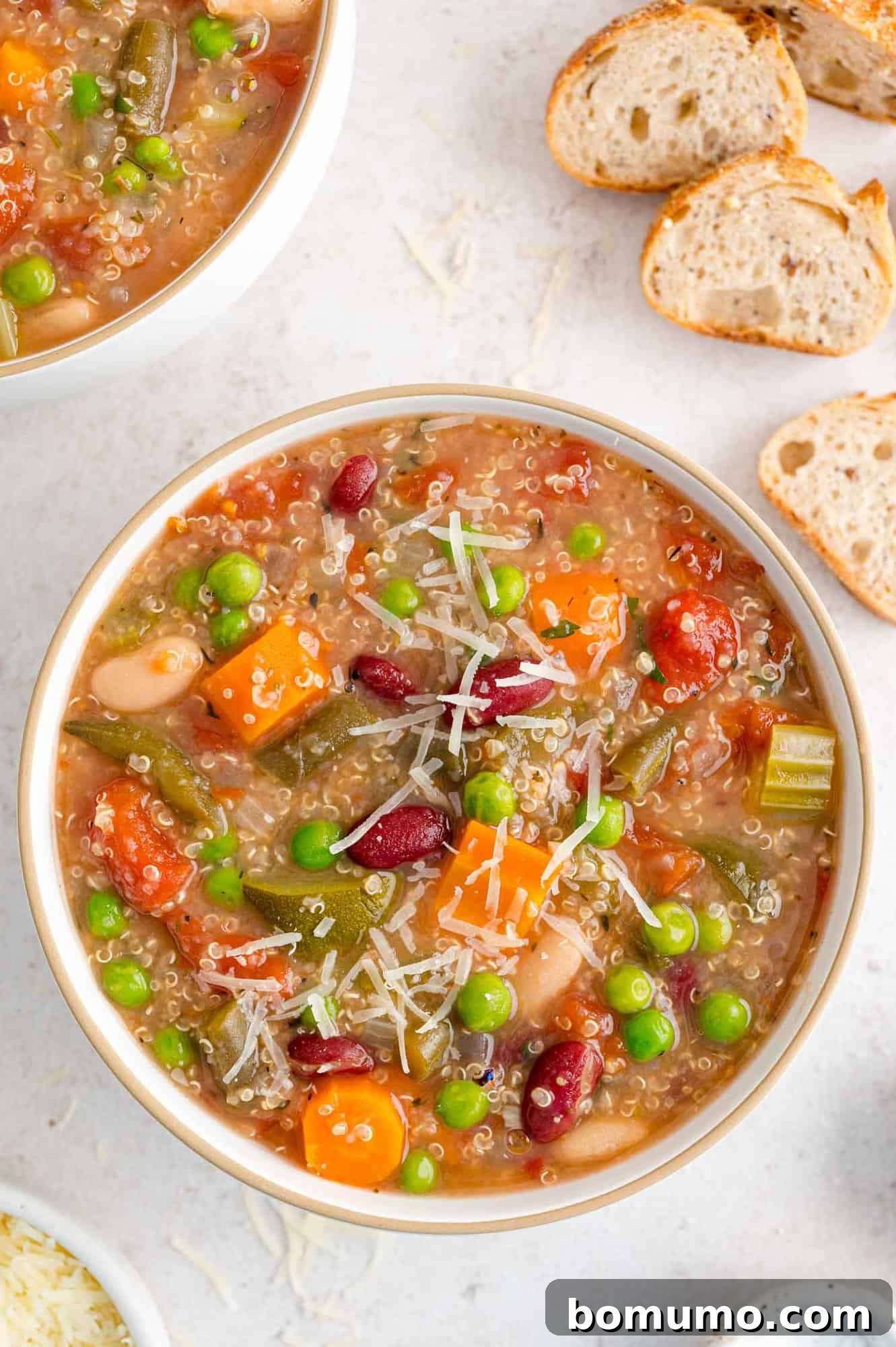Crockpot minestrone soup in a white bowl, garnished with cheese.