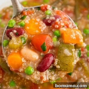 Crockpot minestrone with quinoa, shown in a ladle.