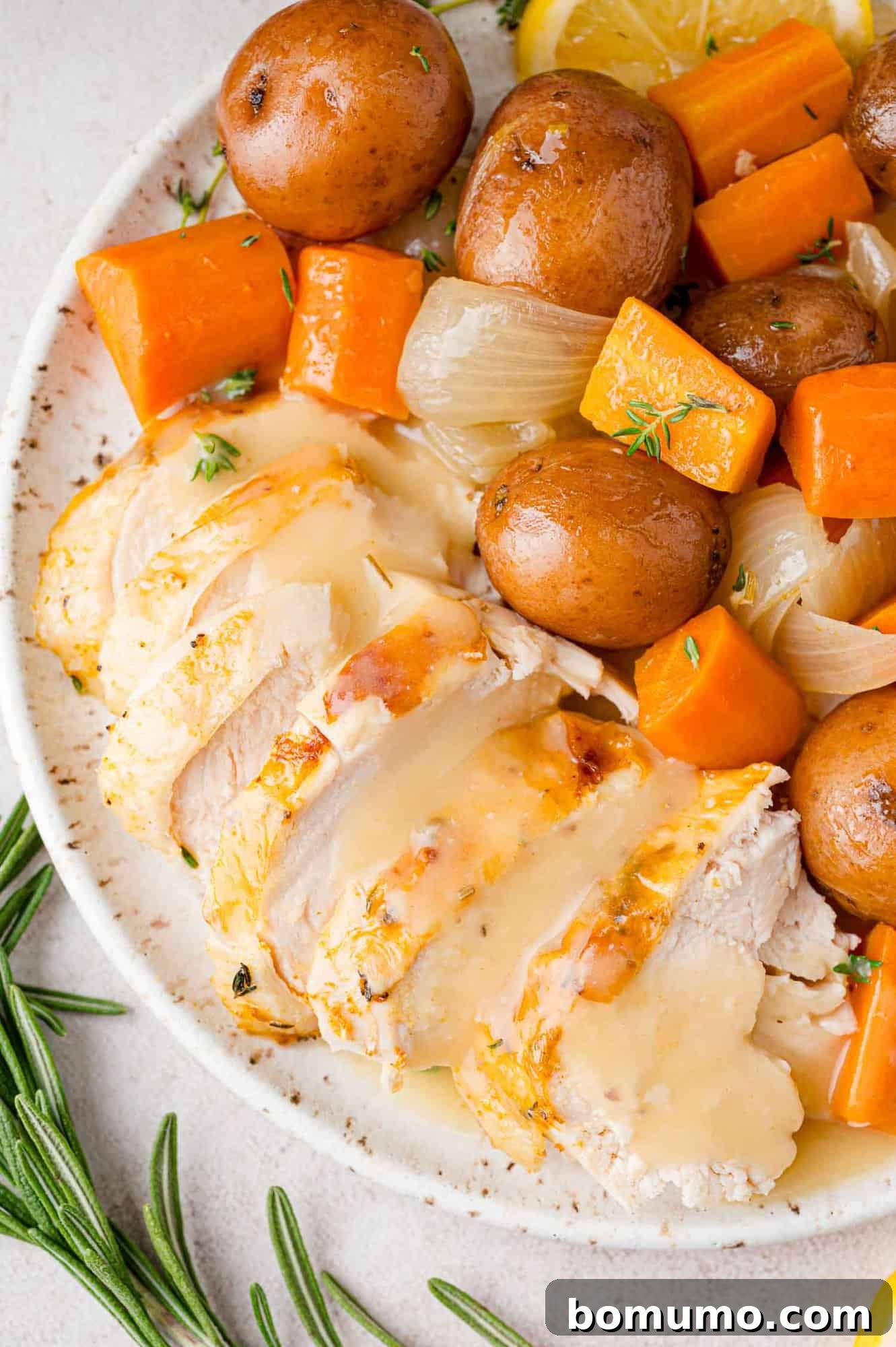 Sliced chicken and gravy on a platter with potatoes and carrots.