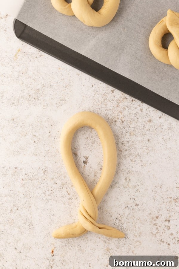 The second step of pretzel shaping: twisting the loose ends of the dough rope twice.