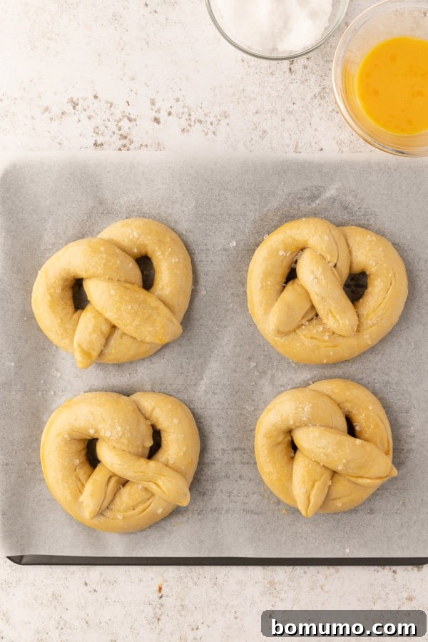 Unbaked pretzels generously sprinkled with coarse salt, ready for the oven.