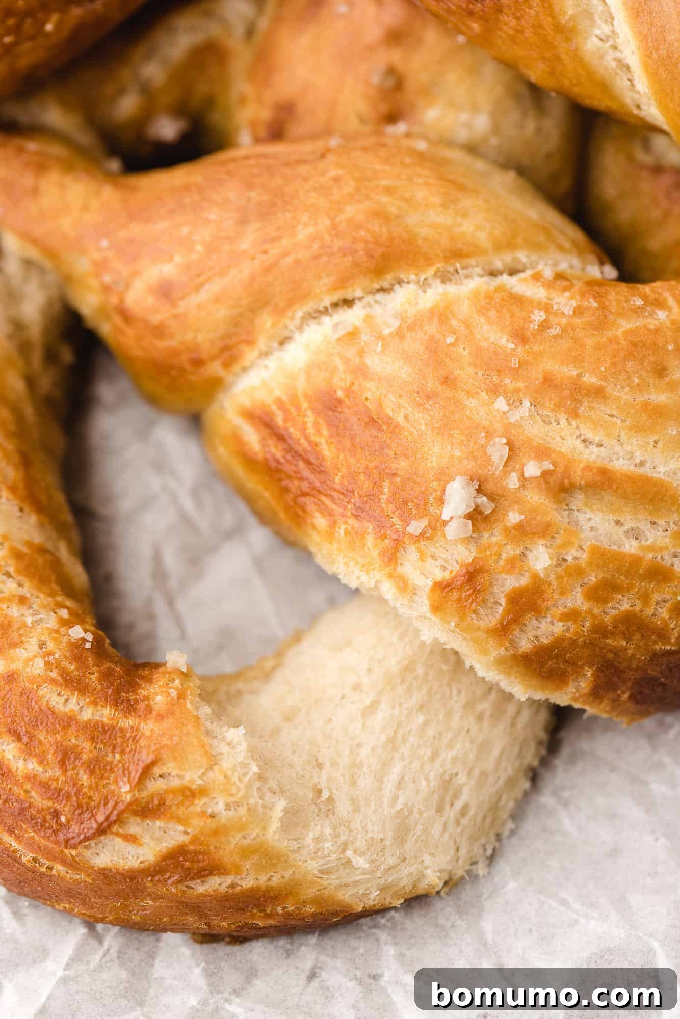 A freshly baked soft pretzel, gently torn to reveal its incredibly soft and fluffy interior.