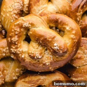 Homemade soft pretzel placed on top of additional pretzels, garnished with salt.