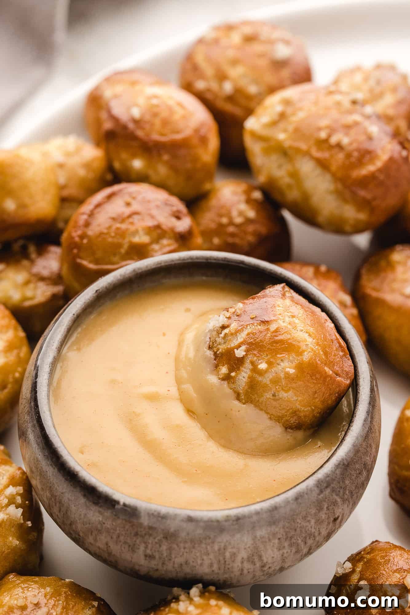 Pretzel bite being dipped in beer cheese dip.