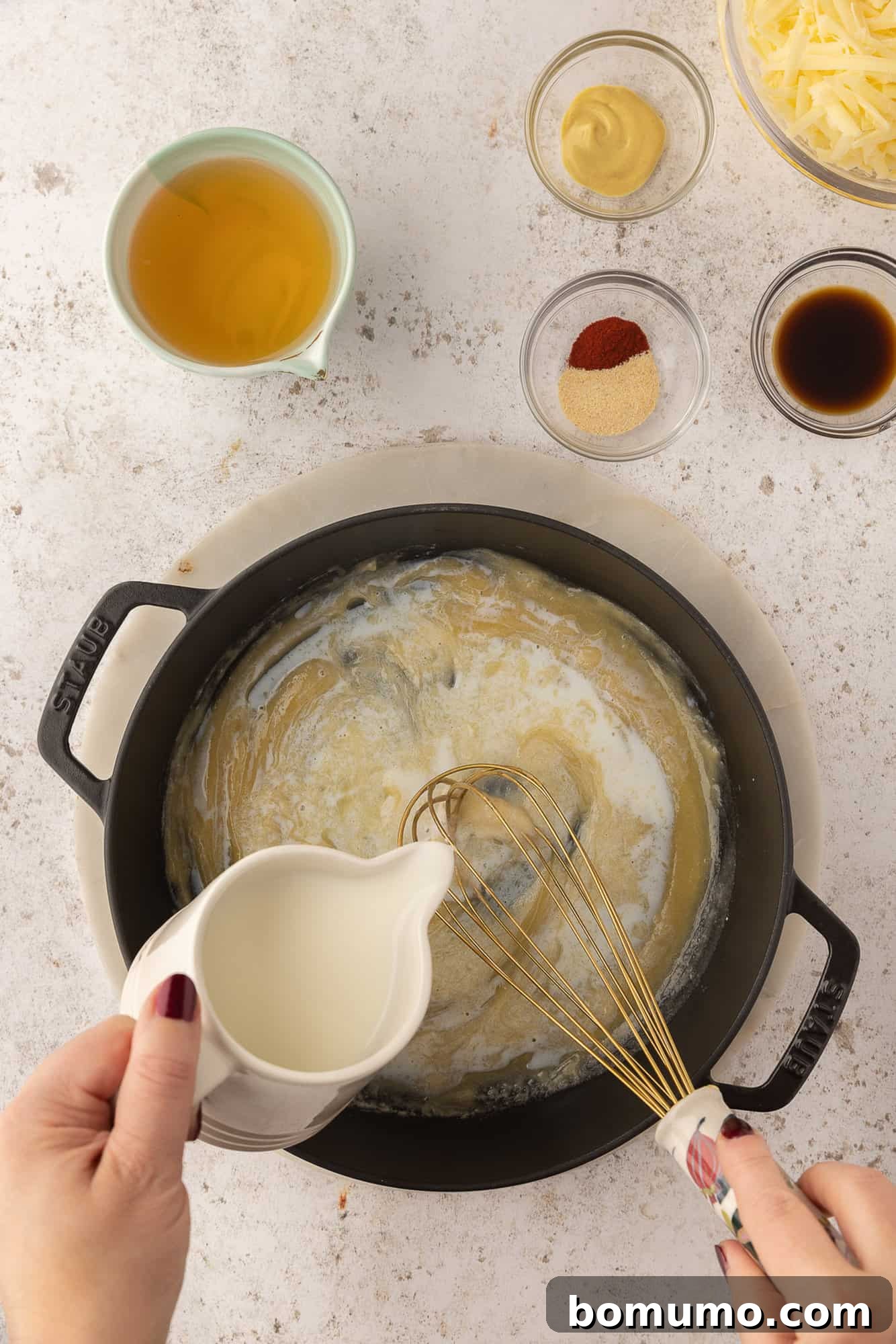 Milk being poured into roux.