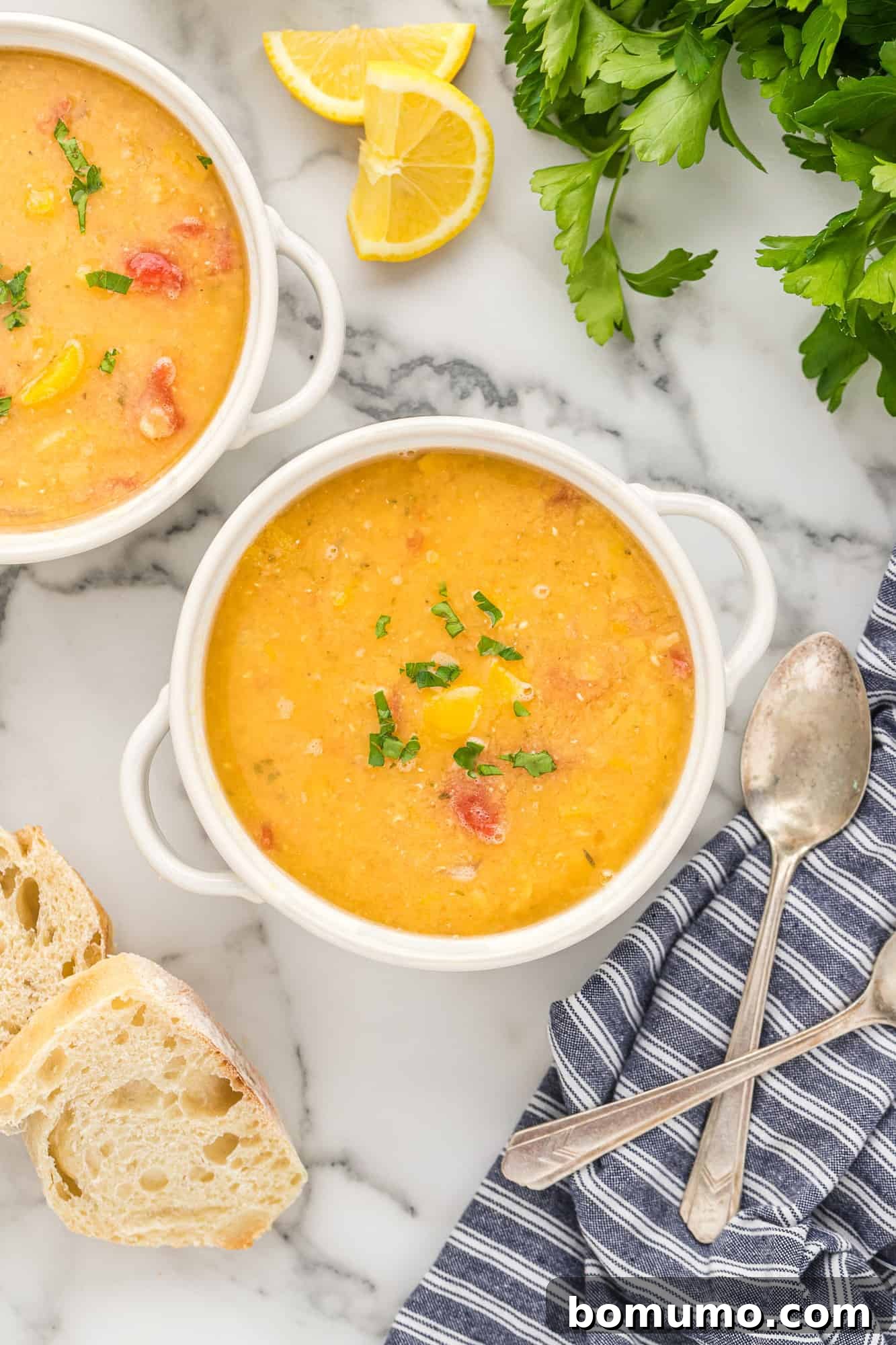 Overhead shot of two inviting bowls of red lentil soup, accompanied by freshly baked bread.