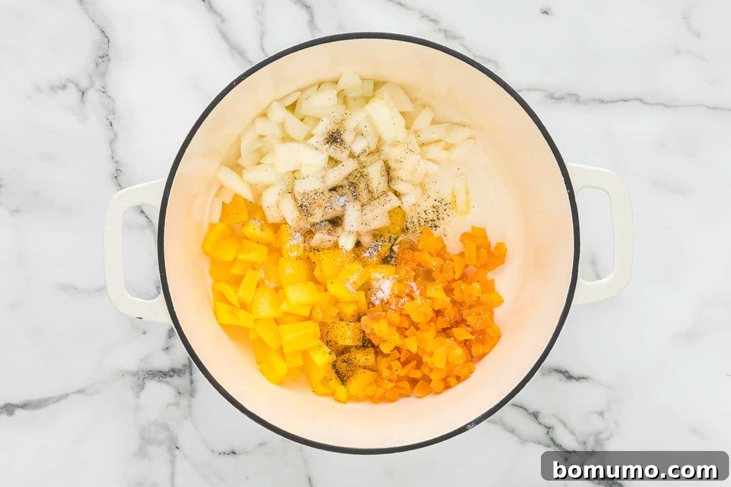 A Dutch oven on the stove, containing sautéed onions, bell peppers, and dried apricots, before the broth is added.