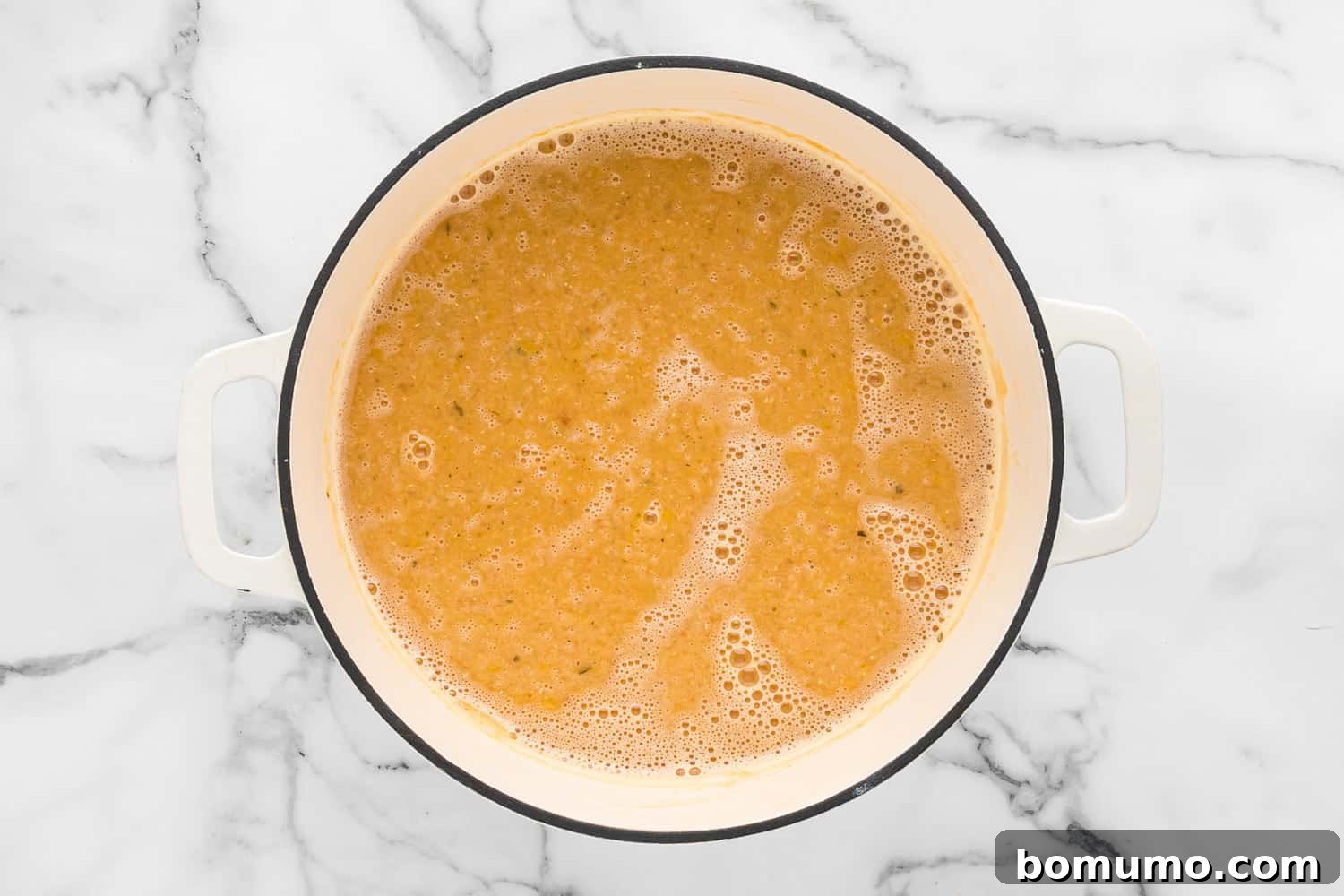 A close-up view of the perfectly cooked red lentil soup, rich and creamy, steaming gently in the pot.